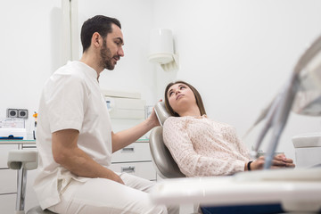 Portrait of a bearded dentist male explaining procedure to a female patient