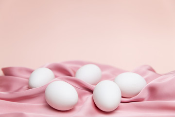 Creative Easter beige and pink background with white eggs.