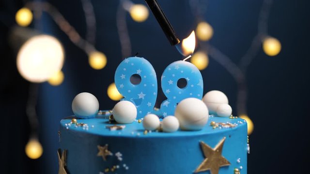 Birthday cake number 99 stars sky and moon concept, blue candle is fire by lighter and then blows out. Copy space on right side of screen if required. Close-up and slow motion