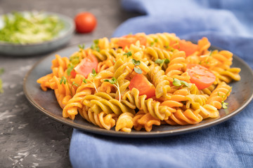 Tortiglioni semolina pasta with tomato and microgreen sprouts on a black concrete background. Side view, selective focus.