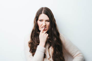 brunette girl bites his nails on a white background