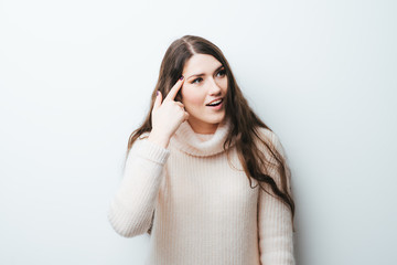 beautiful long-haired girl shows finger to his temple that you're crazy on a white background