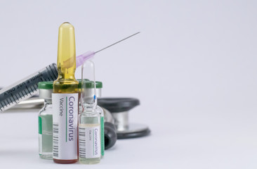 An injection needle leaning on vials behind the Coronavirus Vaccine ampoules.