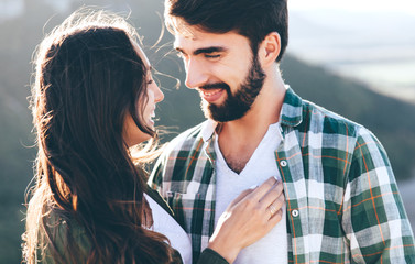 Fototapeta premium Young beautiful couple walking outside on beautiful sunset. Perfect romantic landscape for lovestory. Two hipsters-lovers hugging.