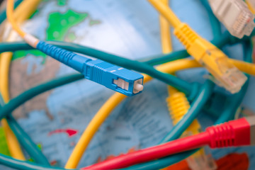 High-speed cable. Fiber optic patch cord is close-up on a background of the globe. Different Internet wires entangle the Earth. . Global Communication Technology Concept