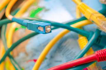 Global Communication Technology Concept. Fiber optic patch cord is close-up on a background of the globe. Different Internet wires entangle the Earth. High-speed cable.