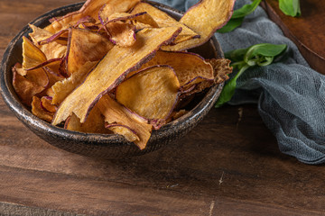 Delicious sweet potato chips in bowl, on table.
