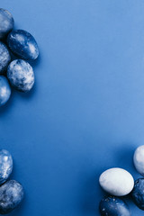 Beautiful group ombre blue Easter eggs with quail eggs and feathers on a blue background. Easter concept. Border eggs. Copy space for text
