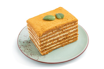 Homemade honey cake with milk cream and mint isolated on white background. Side view.