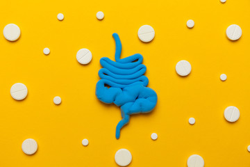 Human intestines with pills on a yellow background. Diarrhea and constipation. Stitches and stomach...