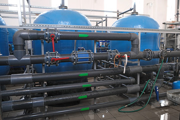 many water pipes and tanks with valves and faucets, wastewater treatment facilities indoors