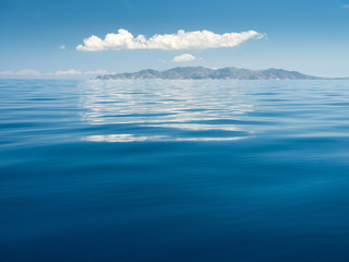 calm sea with reflections of white cloud in the sky