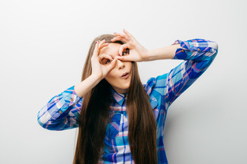 Young happy woman holding her hands over her eyes as glasses and  looking through fingers