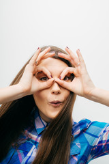 Young happy woman holding her hands over her eyes as glasses and  looking through fingers