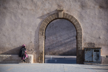 Mujer solitaria musulmana cubierta con burka junto a un arco de piedra en Marruecos