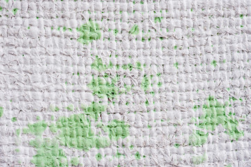 Closeup texture of a roughly painted white and light green canvas lying on a wooden surface. Background for fabric texture. Universal background.
