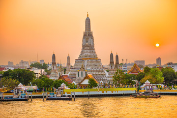 Beautiful Temple of Dawn or Wat Arun and Thonburi west bank of Chao Phraya River at sunset with shining sun. Bangkok, Thailand