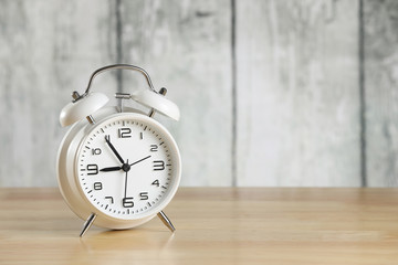 white retro alarm clock on the office table on wooden background. Financial situation. Business issues. Marketing solution
