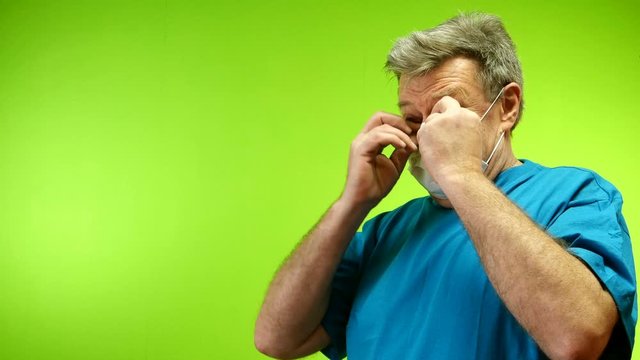 Positive senior adult man put on his protective medical mask which coronavirus protection outside. Optimism and love of life. Green background. Chromakey.