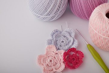 Fototapeta na wymiar A bright set of knitted flowers. Homemade flowers crochet, multi-colored cotton yarn, crochet hooks on a white background with a copy of the space for text. Easy handmade crochet concept