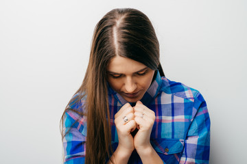 Closeup portrait of young beautiful woman thinks bad news head on his hands folded together into fists. Isolated white background.white background. Negative facial expression emotion feelings