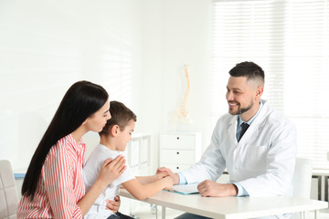 Obraz na płótnie Canvas Little boy with mother visiting orthopedist at clinic