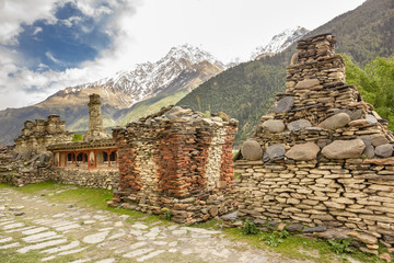 Buddhist stupas, chortens and mani walls made of slabs of stone with the backdrop of snow covered Himalayan mountains in the village of Tukuche in Mustang, Nepal.