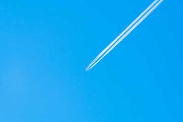Ein Flugzeug mit Kondensstreifen am blauem Himmel