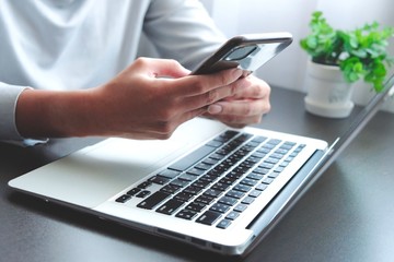 Fototapeta premium The hand of Asian woman holding a mobile phone and press, slide or touch screen for searching about shopping online, chat to lover, prepare information for present to report or using internet banking