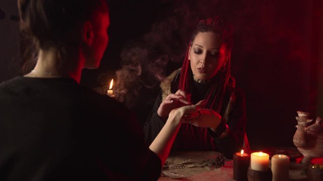 Chiromancer with braids predicting future by hand to woman