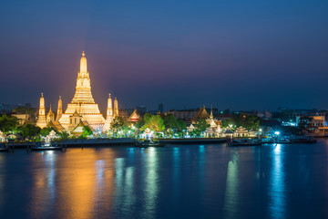 Naklejka premium Night illuminated Temple of Dawn or Wat Arun and its reflection in Chao Phraya River at sunset. Bangkok, Thailand