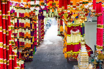 Many indian garlands of colorful flowers for temple and ceremony decoration hanging at asian street...