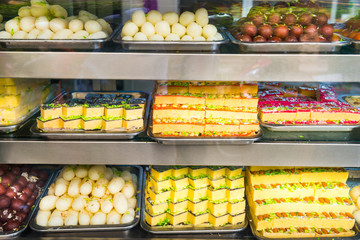 Many delicious traditional indian sweets and desserts at storefront at asian food market