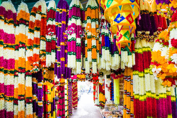 Many indian garlands of colorful flowers for temple and ceremony decoration hanging at asian street market