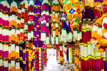 Many indian garlands of colorful flowers for temple and ceremony decoration hanging at asian street...