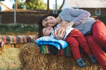laughing mother and son on haystack