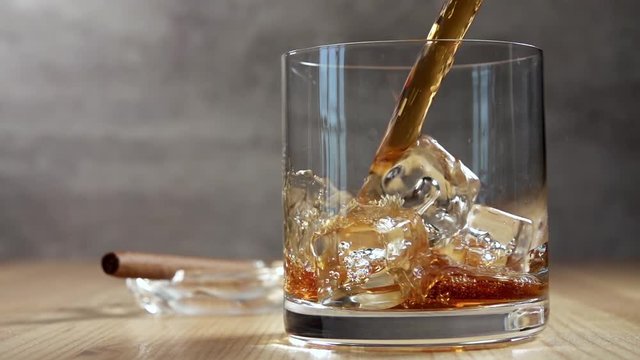 Jet of Whiskey in a Glass With Ice. Slow Motion