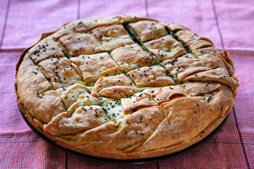 Spinach pie greek spanakopita round shape on kitchen table background