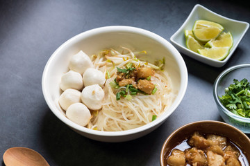 Rice stick noodles with fish ball in white bowl. Garlic cracklings with lard, lime and coriander...