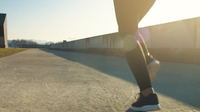 Low angle shot of a woman's legs running, filmed from behind in slow motion