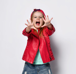 Portrait of beautiful positive blond baby girl kid in bright stylish casual clothing and red cap decorative feeling playful