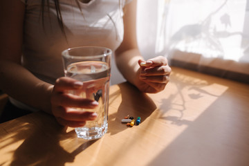 Close up of woman's hands hold pills. Hand with pills and glass of water. Immunity. Vitamines