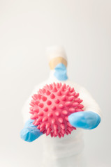 World epidemic of coronavirus.wooden man in protective medical uniform holds COVID-19 virus cell in his hands.The concept of protecting and controlling outbreaks of the SARS epidemic. Copying space.