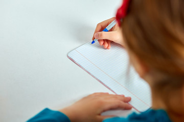 Schoolgirl doing homework, writing, studying lesson, coronavirus home school