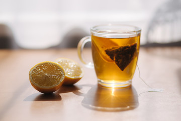 Black tea with lemon on wooden table. Tea bag with lemon slice in cup