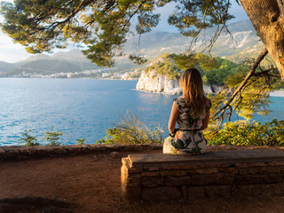 the girl is sitting at sunset in a national Park in Sveti Stefan. Montenegro