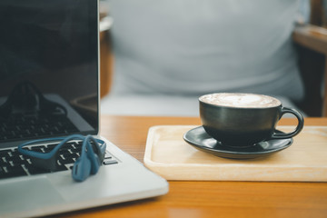 A cup of hot dark chocolate on wooden table with  laptop.