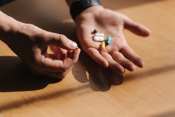 Fototapeta premium Many multi-colored pills on male's hands. Man with watch on hand. Coronavirus concept