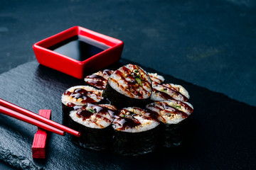 sushi on a black stone tray with chopsticks and sauce