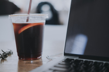 Black iced coffee with a notebook on wood table